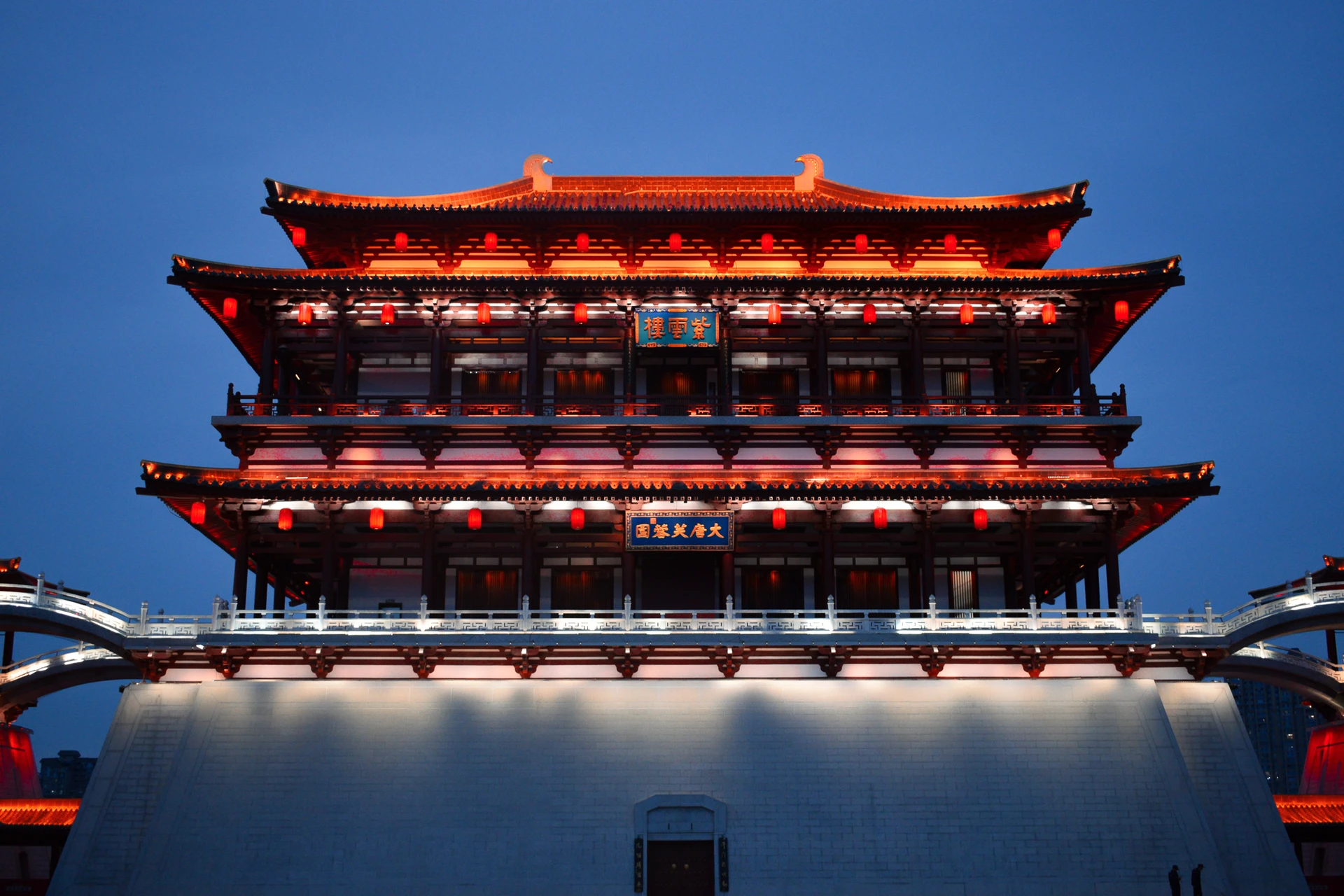 A grand traditional gate outlined in red and gold lights at dusk