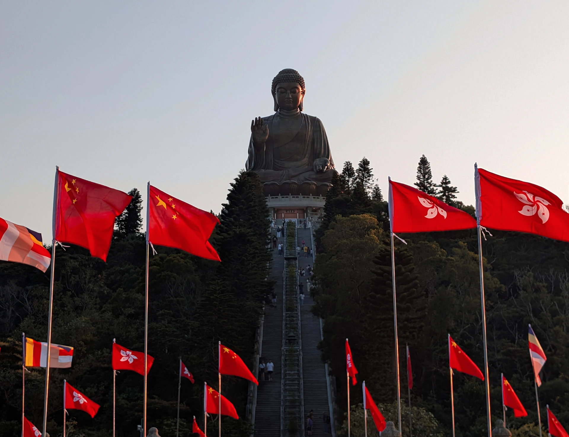 A large seated Buddha above steps lined with red flags