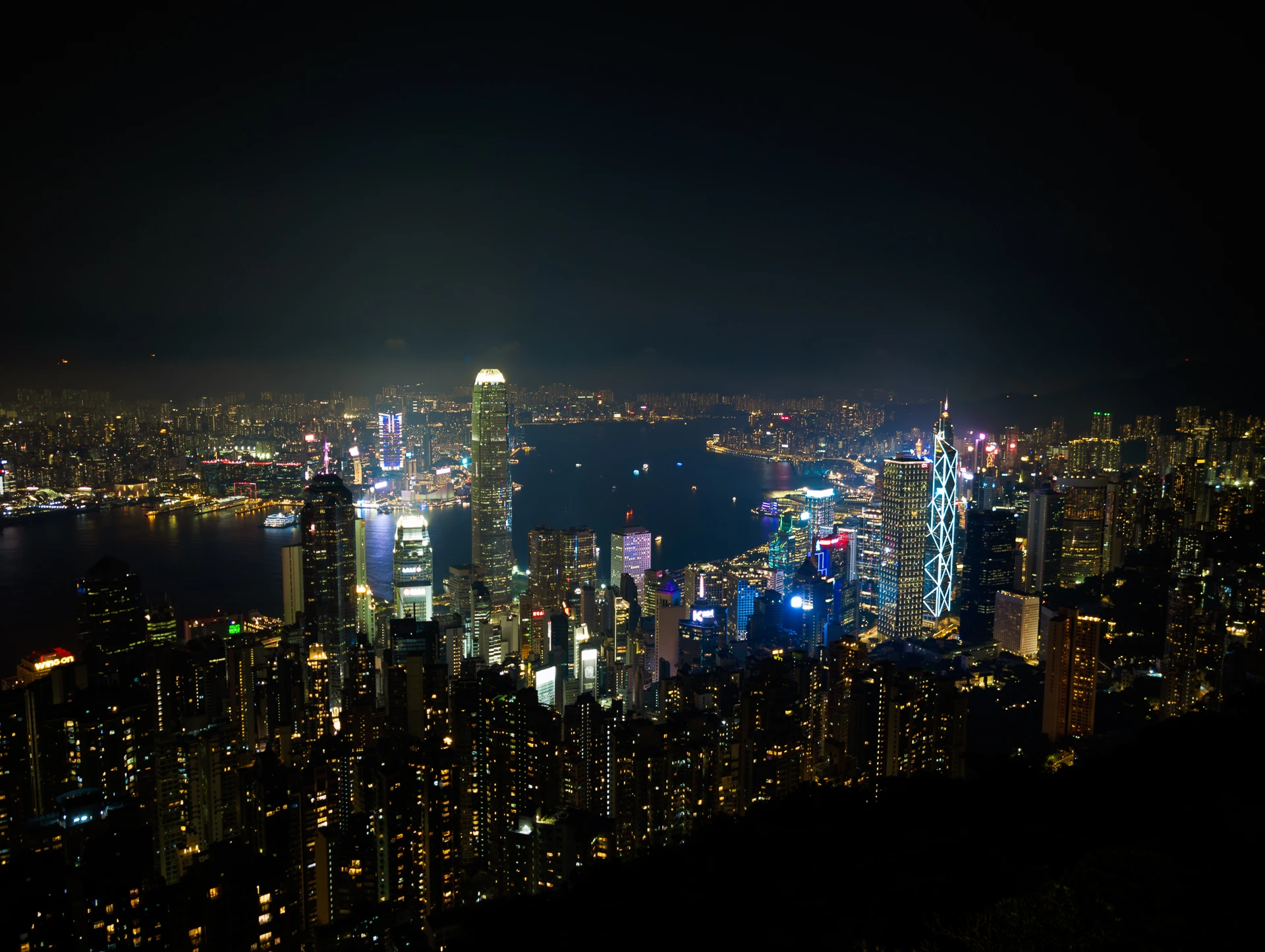 A panorama of a brightly lit city and harbour at night